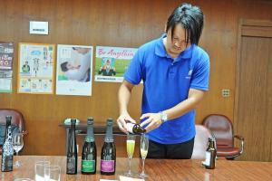 丸孫製茶の鈴木優作さんがワイングラスにスパークリングティーを注いでいる画像です。