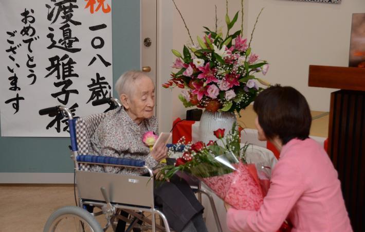 花束を贈る市長と車椅子に座る渡邊雅子さん