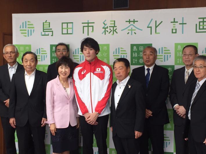 競泳選手の長谷川純矢選手と市長とスーツ姿の男性たちの記念写真