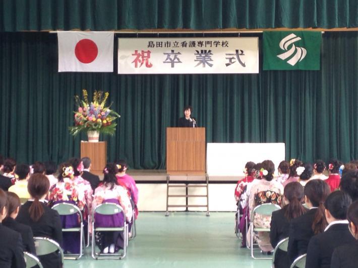卒業式にて袴や着物姿の卒業生を前にして、市長が舞台に立ち挨拶をしている