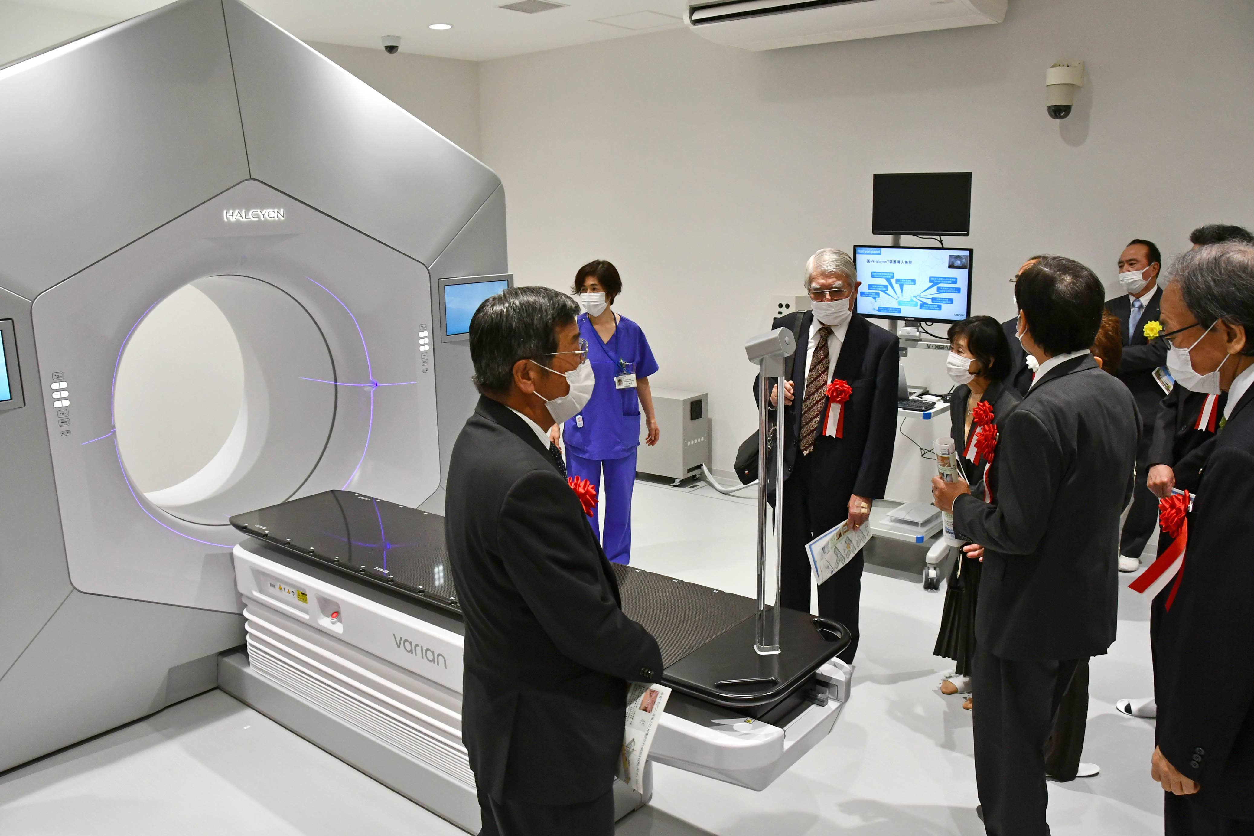 式典出席者に放射線治療装置を紹介する医療従事者