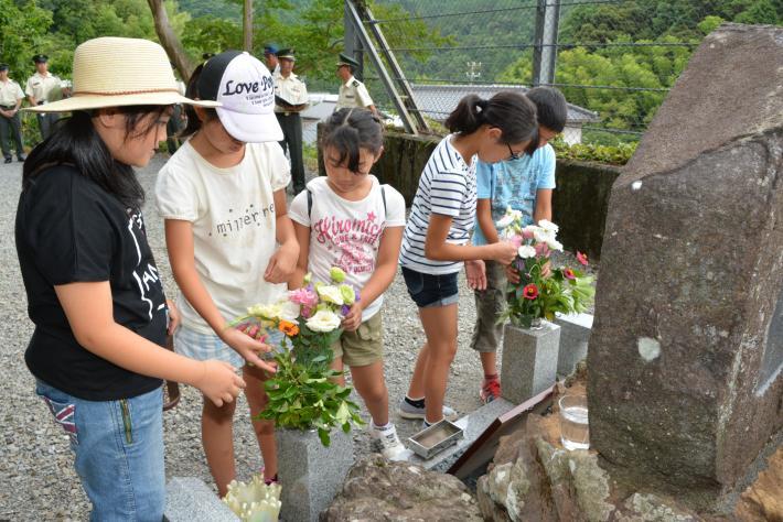 杉の子子ども会の児童5人が慰霊碑に献花する写真