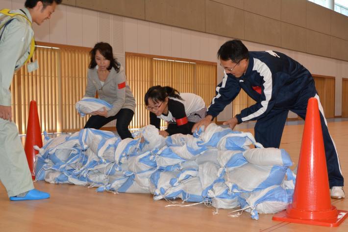 3人で土のう積み上げている写真