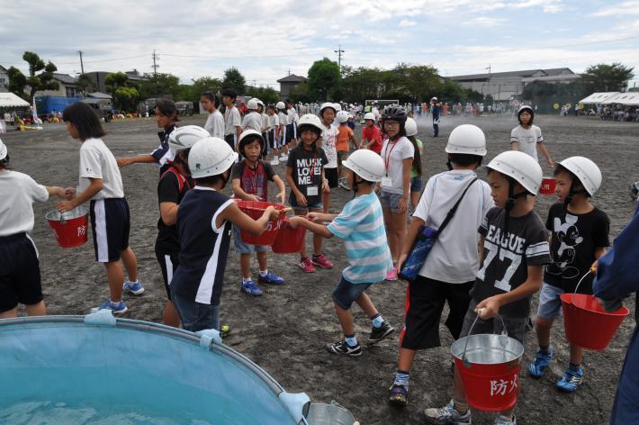 防災訓練で小中学生がバケツリレーをしている写真