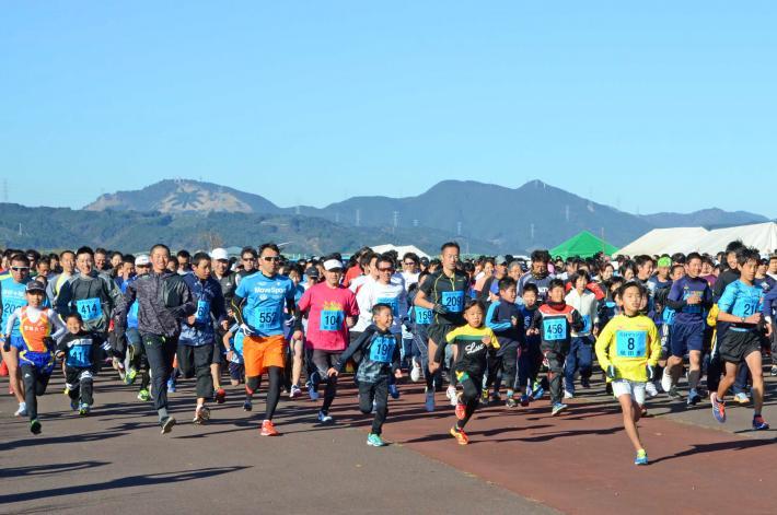 子どもから大人まで走っているマラソン大会の写真