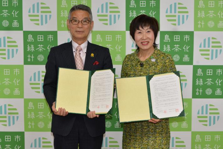 市長と池野代表取締役会長が締結した協定書を手に持つ写真