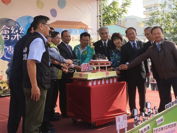 祝賀イベントで参加者がケーキ入刀している写真