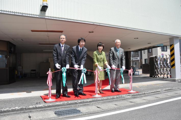 開所式テープカットで4人が並んでいるところ