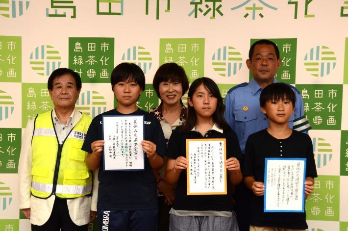 夏休み交通安全宣言書を手にする児童3人と市長らの写真