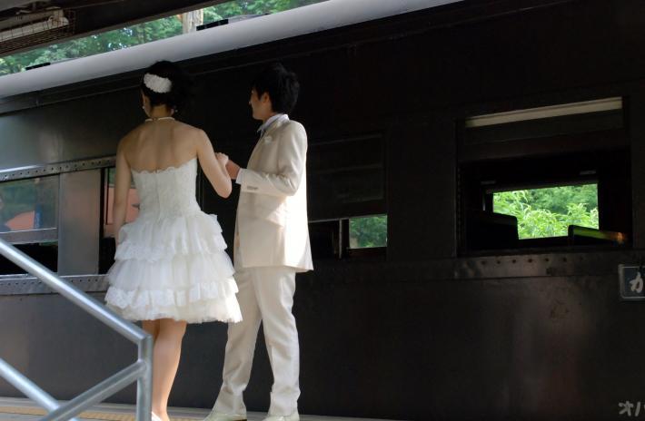 白いタキシード姿の男性と膝丈のウェディングドレス姿の女性が手を取り合っている画像