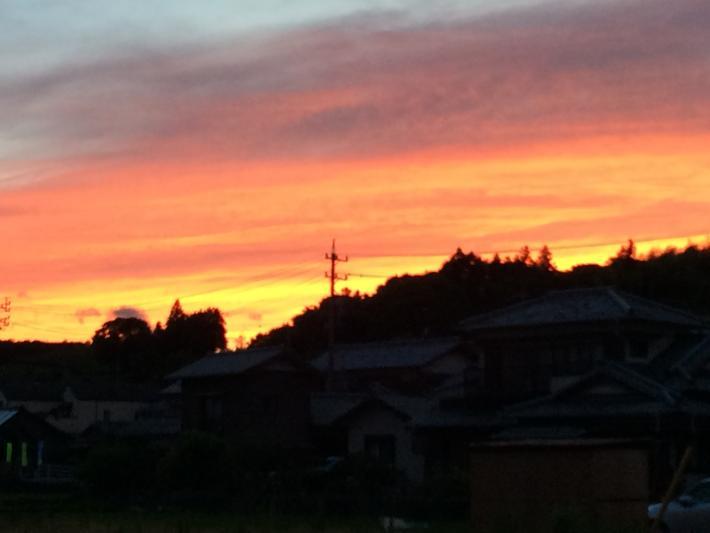 夕日で赤く染まる空と住宅の写真